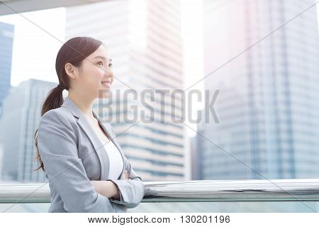 business woman smiles and looks with office background asian beauty shot in Hong Kong