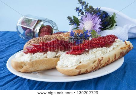 sandwiches with cream cheese and strawberry on a background of spring flowers