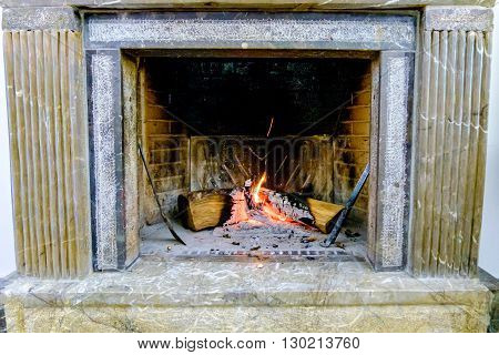 Domestic Marble chimney with burning wood. Italy