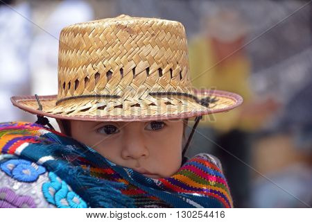 CHICHICASTENANGO GUSTEMALA APRIL 29 2016: Portrait of a Mayan baby carried on the back of his mother. The Mayan people still make up a majority of the population in Guatemala,