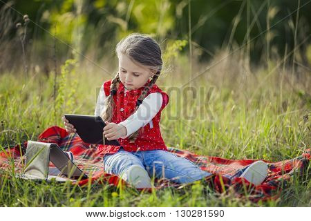 Girl with the tablet on the nature