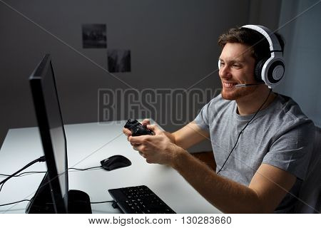 technology, gaming, entertainment, let's play and people concept - happy young man in headset with controller gamepad playing computer game at home and streaming playthrough or walkthrough video