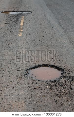 A pothole on a paved road on a rainy day