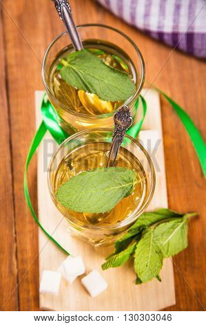 hot fresh tea with green mint and sugar on wooden background