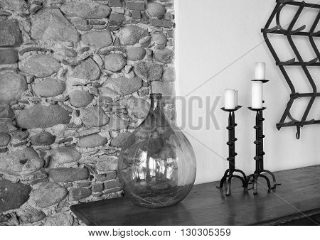 fragment of a room interior with a glass vase and with forged candlesticks a closeup and a stone wall of monochrome tone