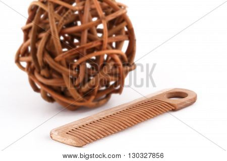 horizontal front view of a wooden comb next to a ball of twisted brown wood branches isolated on white background