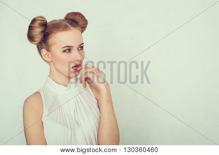 Close-up portrait of thoughtful beautiful girl with funny hairstyle. Sly and scheming young woman face expression.