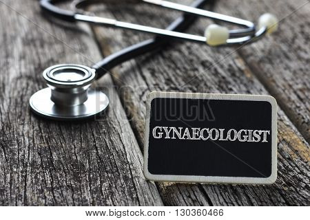 Medical Concept-GYNAECOLOGIST word written on blackboard with Stethoscope on wood background