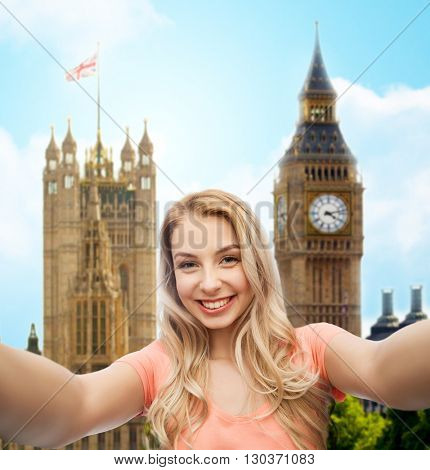 travel, tourism, emotions, expressions and people concept - happy smiling young woman taking selfie over big ben london and city background