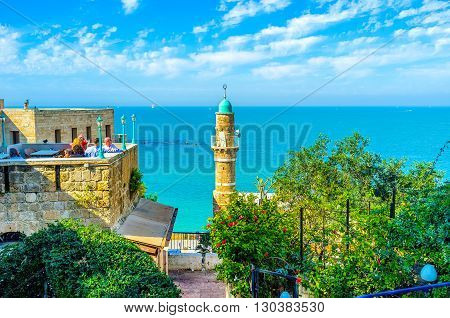 TEL AVIV ISRAEL - FEBRUARY 25 2016: The tourists on the restaurant's roof enjoy the seaside and the medieval architecture of old Jaffa on February 25 in Tel Aviv.