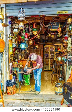 TEL AVIV ISRAEL - FEBRUARY 25 2016: The man polishes the metal detail in the workshop located in the flea market of old Jaffa on February 25 in Tel Aviv.