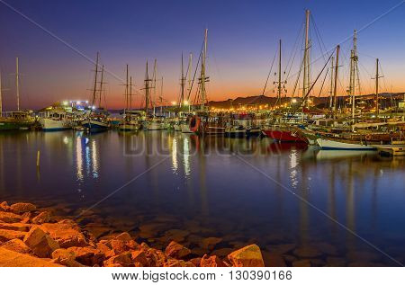 EILAT ISRAEL - FEBRUARY 24 2016: The nice view of the evening port full of yachts and boats with the red twilight sky on the background on February 24 in Eilat.