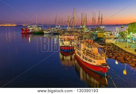 EILAT ISRAEL - FEBRUARY 24 2016: The yachts and pleasure boats surrounded by colorful twilight sky and brightly illuminated water on February 24 in Eilat.