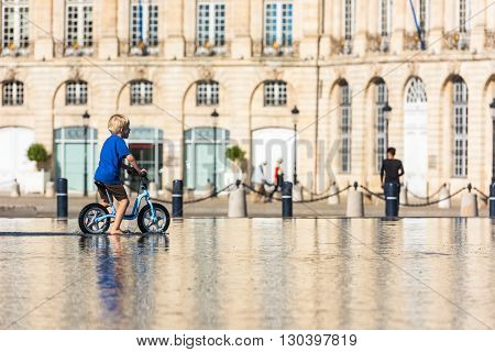 Children Having Fun In A Mirror Fountain In Bordeaux
