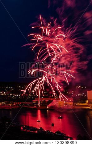 Show of fireworks at the finish of the celebration of the National Day of acceptance on the anniversary of the Norwegian Constitution - May, 17, 2016, Tonsberg, Norway
Can see on picture city by night with port on the Oslofjord port with buildings port.