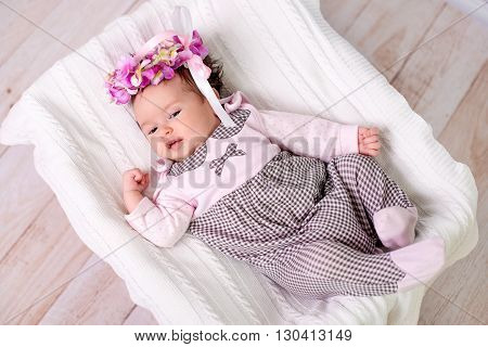 1 month baby girl lies on back looking up and smiling
