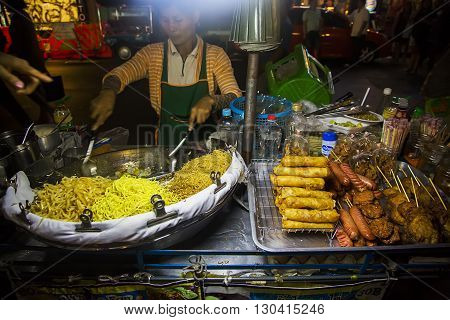 BANGKOK, THAILAND - FEBRUARY 13, 2016: Unidentified woman selling food on the street in Bangkok. Street food is a quintessential part of the Bangkok experience.
