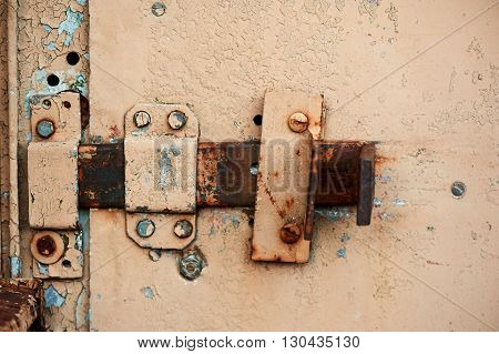 An orange metal garage door, with a hinged lock and lock cover.