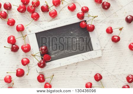 Fresh cherries around empty chalkboard.  Overhead view, blank space