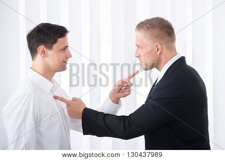 Portrait Of Two Young Businessmen Pointing Finger At Each Other