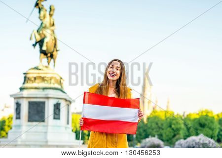 Young smiling woman holding austrian flag on Helden square in Vienna.