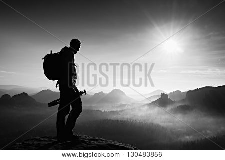 Silhouette of photographer overlooking a blanket of fog over valley to sun
