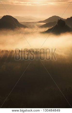 Distant Mountain Range And Heavy Clouds Of Colorful  Mist Above Deep Valleys