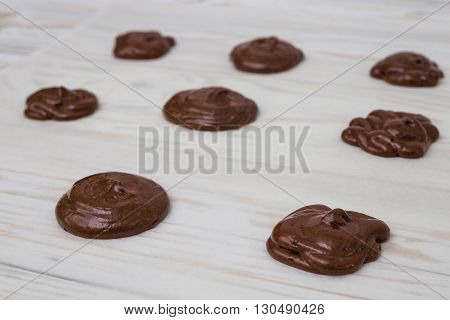 Unbaked chocolate Whoopie pies on white wooden bsckground