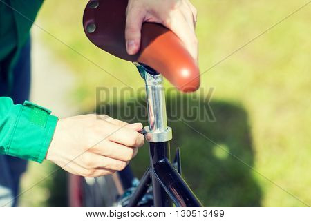 people, vehicle, eisure and lifestyle - close up of man adjusting fixed gear bike saddle high