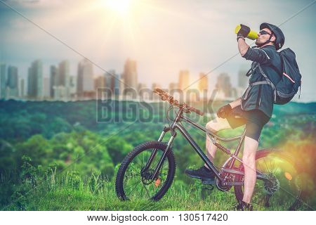 Mountain Biking Near the City. Mountain Biker Refreshing His Body By Drinking Fresh Cold Water.