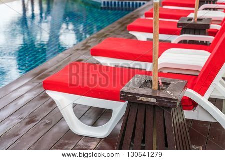 Beautiful beach chairs with umbrella around outdoor swimming pool neary sand and sea
