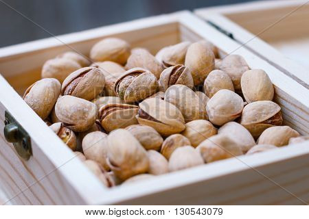 Pistachio nuts in a shell, salty, roasted in a wooden box