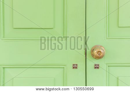 Vintage golden knob on the green wood door. Croped composition.
