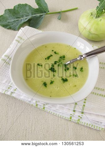 Homemade kohlrabi cream soup in bowl and fresh vegetable
