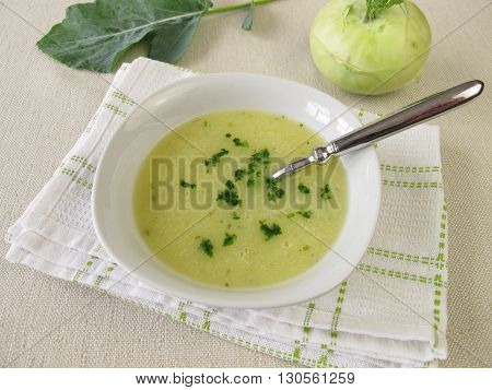 Homemade kohlrabi cream soup in bowl and fresh vegetable