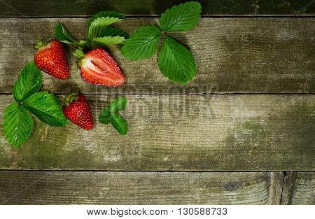 Two and a one half strawberrys on a old wooden background