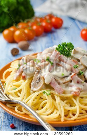 Spaghetti with Bechamel sauce mushrooms and bacon on a wooden table