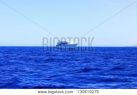 Sea Blue Water Background at Sun Light. White Ship floats on Water.