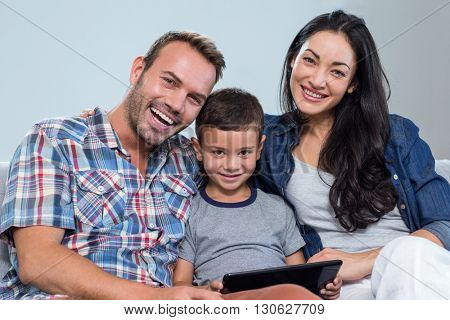Mother and father sitting together with son and using digital tablet