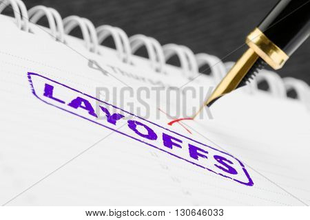 Macro shot of layoffs stamp and fountain pen on a scheduler.