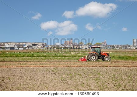 NAGOYA JAPAN - April 16, 2016: Farmer in tractor preparing land for sowing. Farmer in tractor preparing land with seedbed cultivator on April 16, 2016.