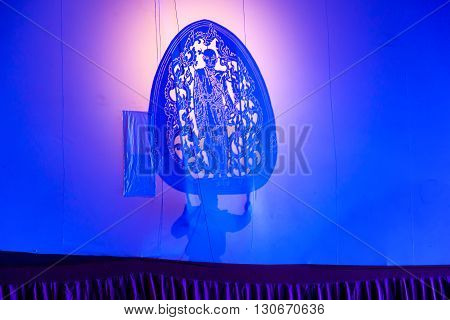 RATCHABURI THAILAND - APRIL 14 2015: The Cowskin shows a man holding a stencil pattern. Moving Cowskin the light to shadow play. The musical atmosphere and read a poem composed. In a traditional culture. There are performances every year Thailand in SONGK
