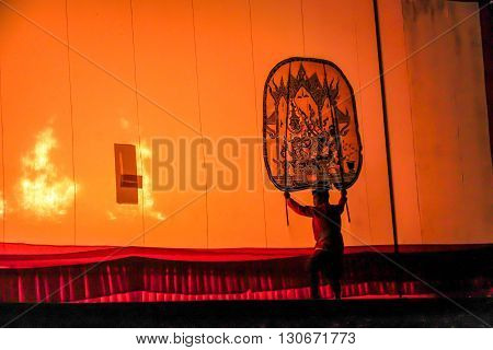 RATCHABURI THAILAND - APRIL 14 2015: The Cowskin shows a man holding a stencil pattern. Moving Cowskin the light to shadow play. The musical atmosphere and read a poem composed. In a traditional culture. There are performances every year Thailand in SONGK