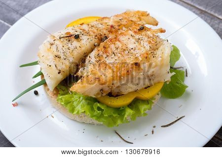 Fishburger with pepper and salat lettuce on the stone plate