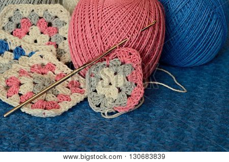 Crochet motives hook and cotton yarn on a blue background