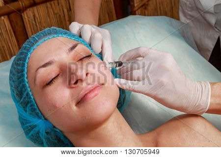 Cosmetic injection in the spa salon. Beautician makes injection into the patient's face. Beauty injections mesotherapy revitalization cosmetic medicine injection - the concept of rejuvenation.