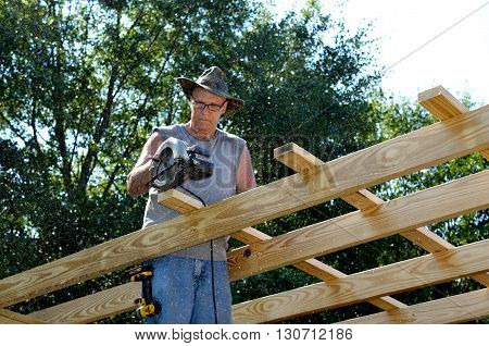 Man building roof add on too shop.  Active middle age senior working on DYI construction project