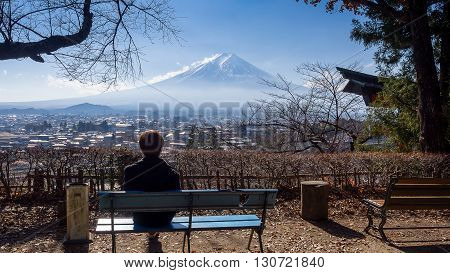 A man sitting on a bench seeing Mt. Fuji with clear sky alone