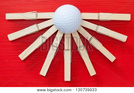 Set of cloth pegs and golf ball on wooden red table