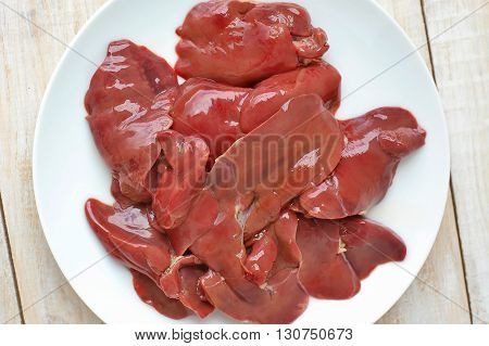 Raw Liver On The White Plate On The Wooden Background